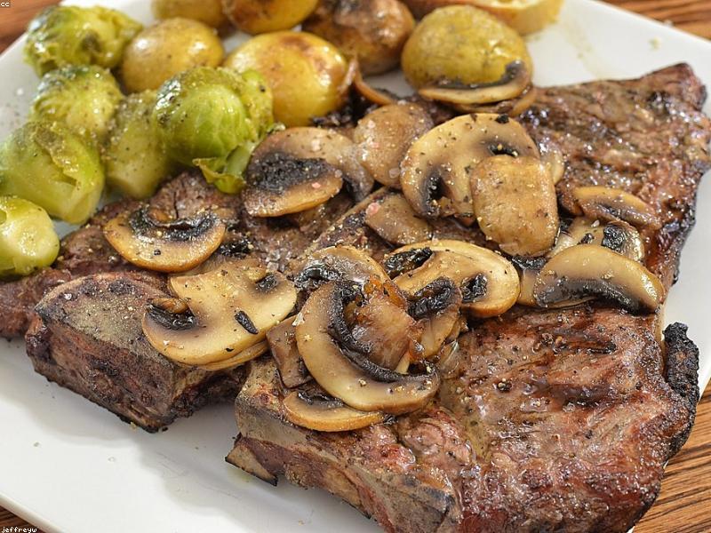 A juicy grilled steak with grill marks, garnished with rosemary on a wooden board