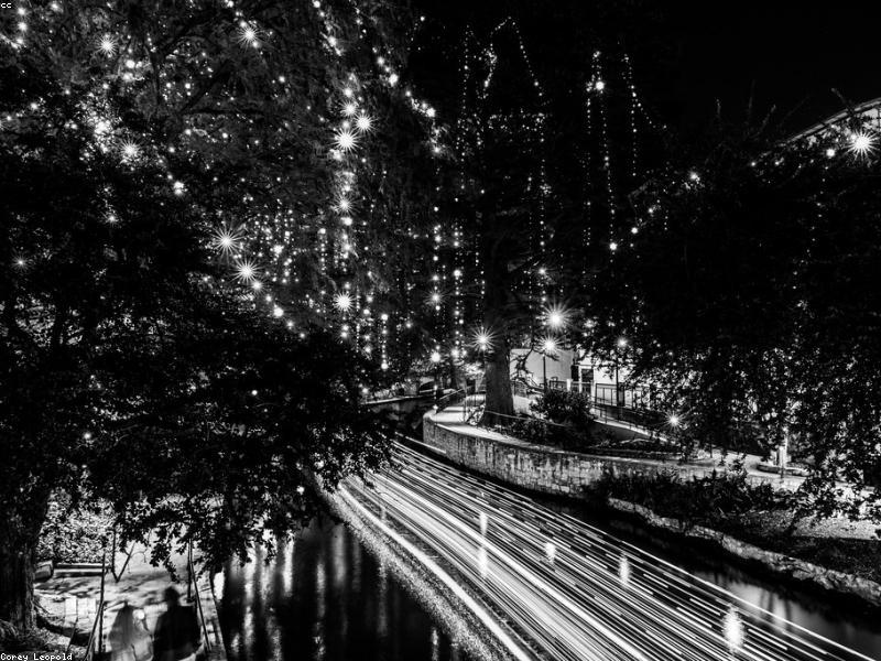 Couple walking along the San Antonio River Walk at night with lights
