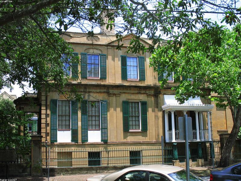Couple walking hand in hand in Savannah's Historic District with oak trees