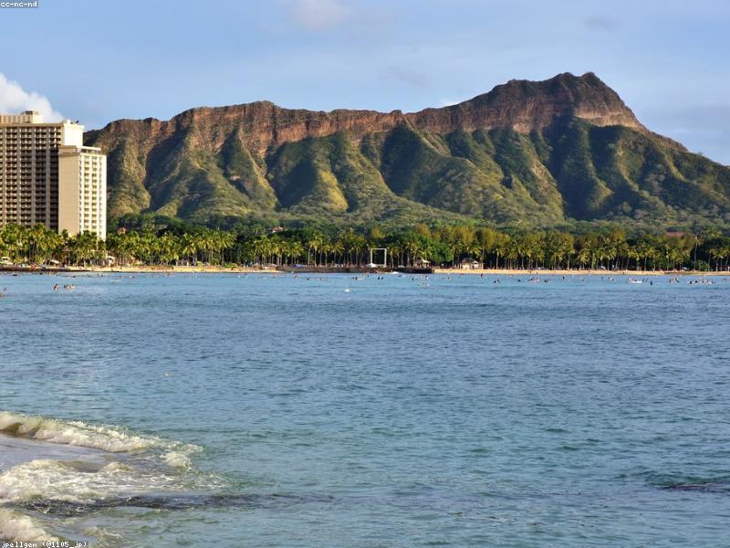 Couple walking on Waikiki Beach at sunset with Diamond Head in background
